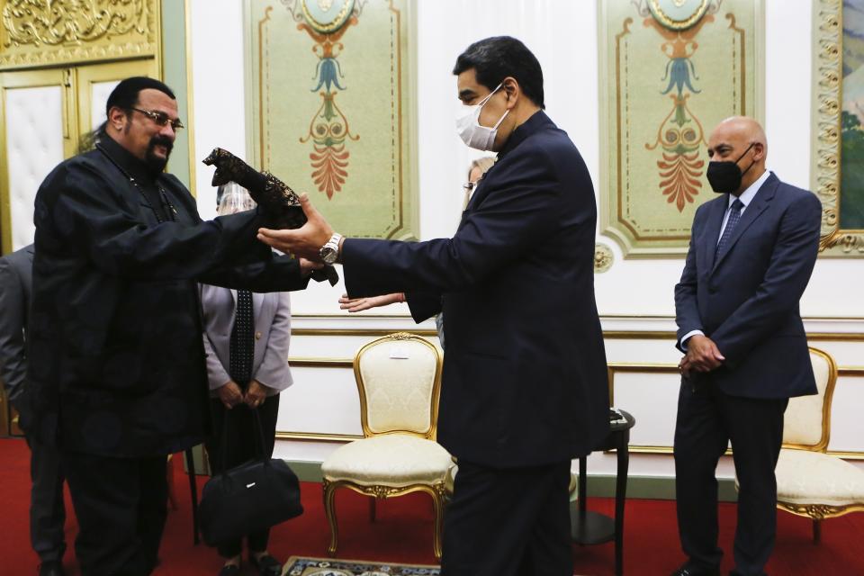 En esta imagen proporcionada por la oficina de prensa de Miraflores, el actor Steven Seagal, a la izquierda, le entrega al presidente venezolano Nicolás Maduro una espada samurai, en el palacio presidencial en Caracas, Venezuela, el martes 4 de mayo de 2021. (Oficina de prensa de Miraflores vía AP)