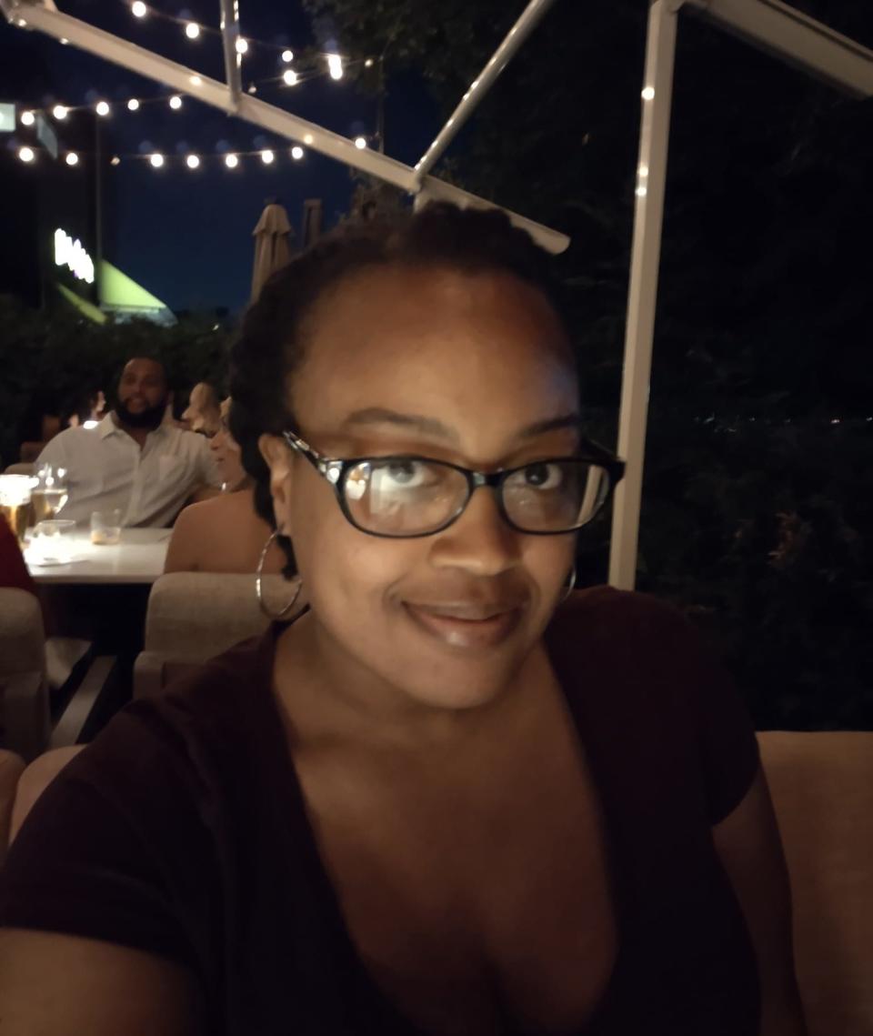 A woman at a dark restaurant wearing black glasses and a black top