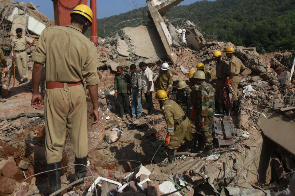 Rescue workers look at a body stuck in the debris of a building that collapsed in Canacona, about 70 kilometers (44 miles) from Goa state capital Panaji, India, Sunday, Jan. 5, 2014. The five-story building under construction in the southern Indian state of Goa collapsed on Saturday, killing at least a dozen people and leaving dozens more feared trapped under the rubble, police said. (AP Photo/Rafiq Maqbool)