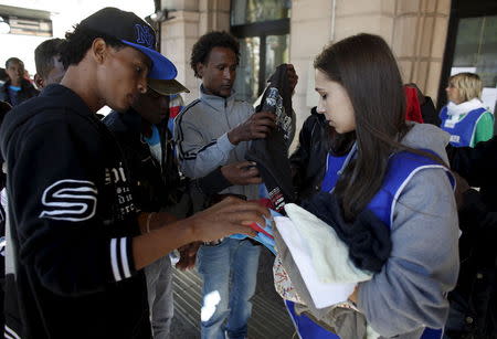 Dejen Asefaw (L), a 24-year-old Eritrean, gets a piece of clothing from a volunteer at the Bolzano railway station, northern Italy, May 28, 2015. REUTERS/Stefano Rellandini