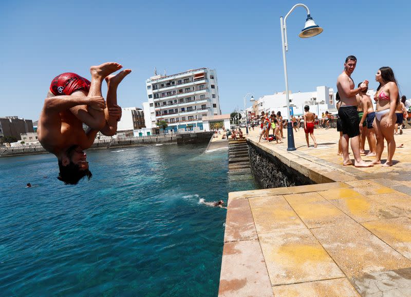 A young man jumps to bathe on Arinaga Beach as some Spanish provinces are allowed to ease lockdown restrictions during phase two, on the island of Gran Canaria