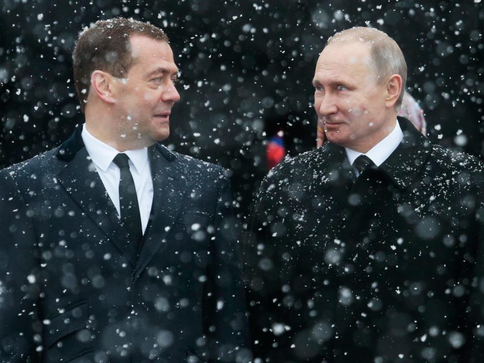 Dmitry Medvedev and Vladimir Putin looking at each other while it's snowing.