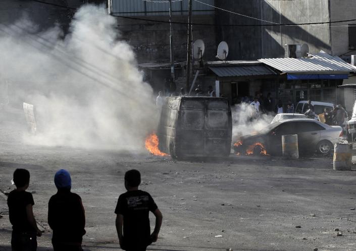 Palestinian youth look at burning cars during clashes with Israeli security forces in east Jerusalem on October 30, 2014 (AFP Photo/Ahmad Gharabli)