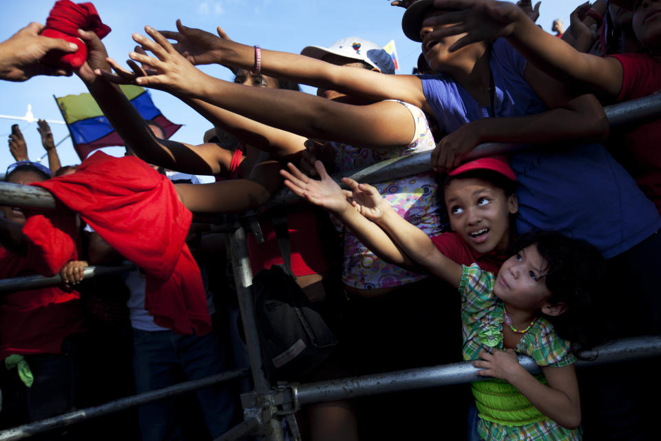 Supporters reach out for campaign swag as they wait for Venezuela's President Hugo Chavez to deleiver his speech at a campaign rally in Guarenas, Venezuela, Saturday, Sept. 29, 2012. Venezuela's presidential election is scheduled for Oct. 7. (AP Photo/Rodrigo Abd)