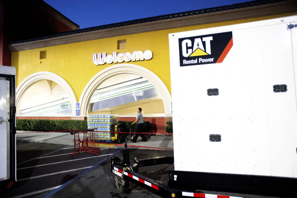 A portable generator powers a Lucky supermarket in Oakland, Calif., as Ruben Imperial moves water on Thursday, Oct. 10, 2019. The area remains without power after Pacific Gas and Electric cut service hoping to prevent wildfires during dry, windy conditions throughout Northern California. (AP Photo/Noah Berger)