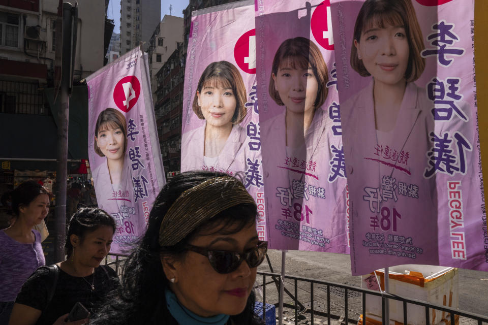 Pedestrians walk past posters promoting candidates during the District Council elections in Hong Kong, Sunday, Dec. 10, 2023. Residents went to the polls on Sunday in Hong Kong's first district council elections since an electoral overhaul was implemented under Beijing's guidance of “patriots” administering the city, effectively shutting out all pro-democracy candidates. (AP Photo/Louise Delmotte)