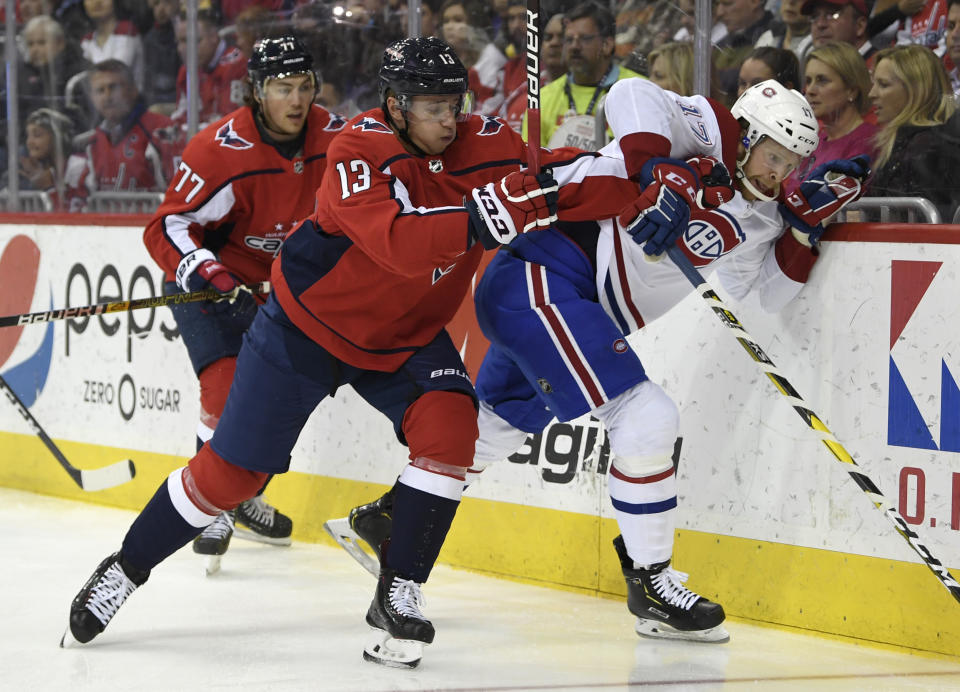 Washington Capitals left wing Jakub Vrana (13), of the Czech Republic, pushes Montreal Canadiens defenseman Brett Kulak (17) up against the board as Washington Capitals right wing T.J. Oshie (77) trails during the second period of their NHL hockey game in Washington, Thursday, April 4, 2019. (AP Photo/Susan Walsh)