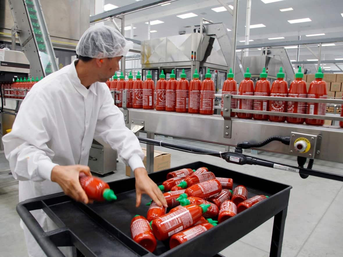 Bottles of the popular sriracha hot sauce could be hard to find on store shelves this summer, after its producer had to suspend production due to pepper shortages. (Nick Ut/The Associated Press - image credit)