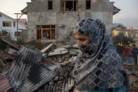 Kashmiri villagers inspect the debris of a house destroyed in a gunfight in Pampore, south of Srinagar, Indian controlled Kashmir, Saturday, Oct. 16, 2021. Indian government forces killed five rebels in last 24-hours in disputed Kashmir on Saturday, officials said, as violence increased in recent weeks. (AP Photo/Dar Yasin)