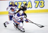 Edmonton Oilers defenseman Darnell Nurse (25) and forward Ryan Nugent-Hopkins (93) check Calgary Flames forward Nazem Kadri (91) during the second period of an NHL hockey game Saturday, April 6, 2024, in Calgary, Alberta. (Jeff McIntosh/The Canadian Press via AP)