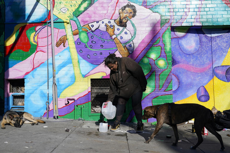 Victoria Solomon pours water for her two dogs Gypsy, left, and Chunx, right, in San Francisco, Monday, Dec. 12, 2022. (AP Photo/Godofredo A. Vásquez)