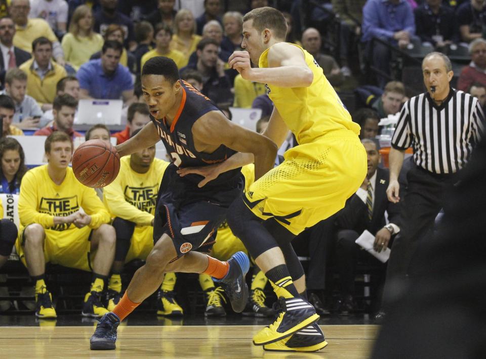 Illinois guard Joseph Bertrand, left, drives the ball against Michigan guard Nik Stauskas in the first half of an NCAA college basketball game in the quarterfinals of the Big Ten Conference tournament Friday, March 14, 2014, in Indianapolis. (AP Photo/Kiichiro Sato)