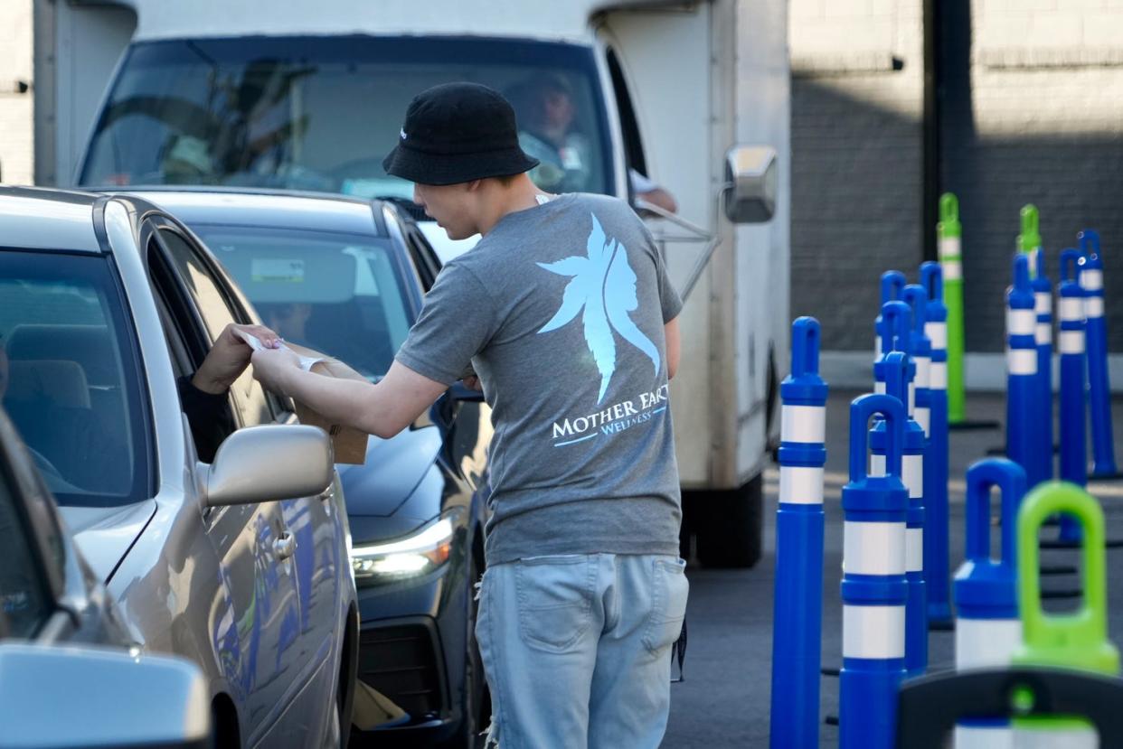 Kevin Chan of Mother Earth Wellness, in Pawtucket, delivers an order to a drive-thru customer last week. According to Joe Pakuris, the dispensary's owner, his is the only marijuana drive-thru in New England.