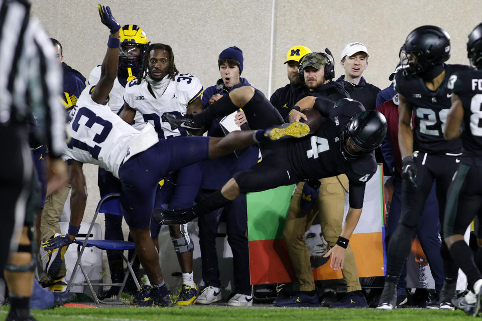 Michigan State quarterback Sam Leavitt (4) is hit out of bounds by Michigan defensive back DJ Waller Jr. (13) during the second half of an NCAA college football game, Saturday, Oct. 21, 2023, in East Lansing, Mich. Waller was penalized for a late hit. (AP Photo/Al Goldis)