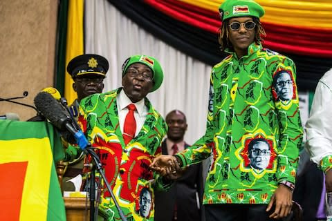 Robert Mugabe with his eldest son Robert Mugabe Junior at a party meeting in October - Credit: AFP