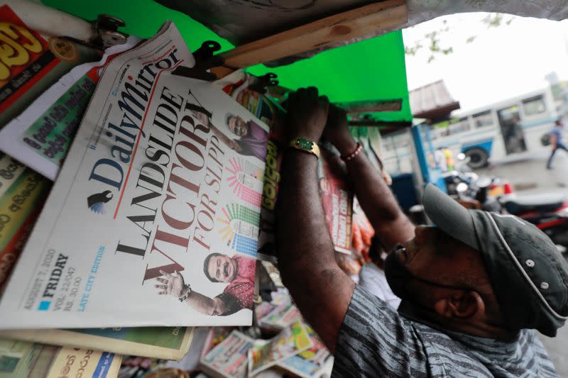 A man hangs newspapers carrying headlines about the victory of Mahinda Rajapaksa's Sri Lanka People's Front party in the country's parliamentary election in Colombo