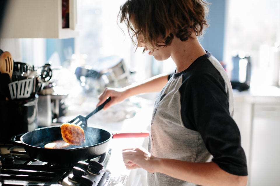 A person flipping food in a cast-iron skillet that is smoking