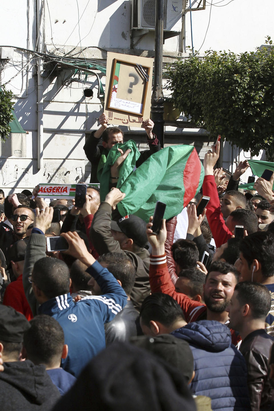 A demonstrator holds a presidential portrait with the question mark during a march in the streets of the Algerian capital, Algiers, to denounce President Abdelaziz Bouteflika's bid for a fifth term, Friday, Feb. 23, 2019. The 81-year-old Bouteflika announced this month that he plans to seek a new term in April presidential elections despite serious questions over his fitness for office after a 2013 stroke left him largely infirm. (AP Photo/Anis Belghoul)