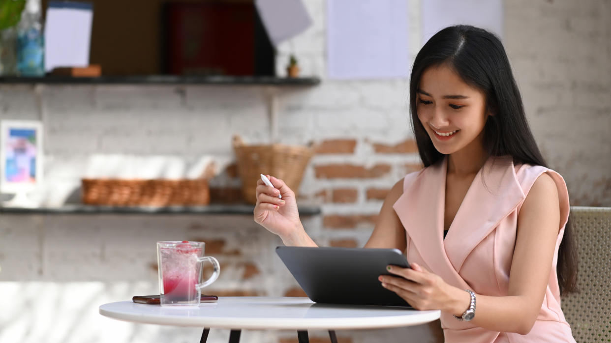 Cheerful businesswoman planing work with digital tablet while sitting in cafe.