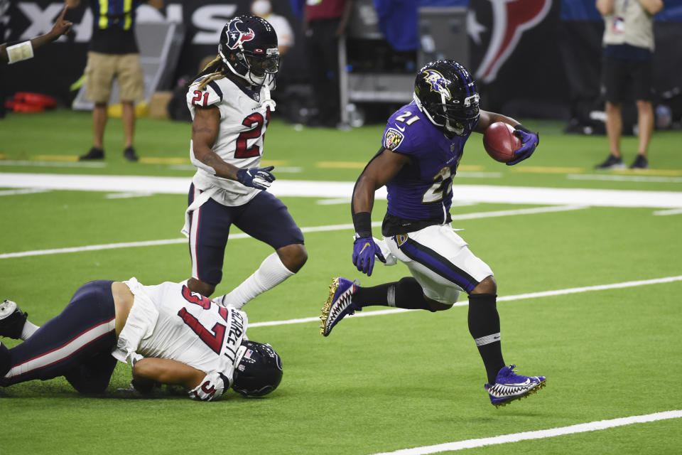 Mark Ingram runs with the ball as Texans defenders look on.