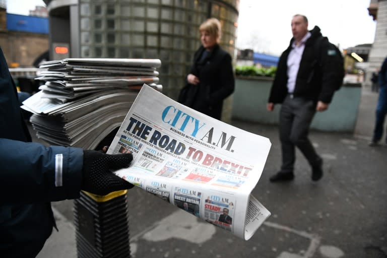 A man hands out copies of the City A.M. newspaper outside Waterloo station in central London on March 29, 2017