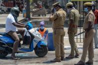 Policemen stand beside as a health worker (C) sprays disinfectant on a scooter coming out of a market during a government-imposed nationwide lockdown as a preventive measure against the COVID-19 coronavirus, in Chennai on March 27, 2020. (Photo by Arun SANKAR / AFP) (Photo by ARUN SANKAR/AFP via Getty Images)