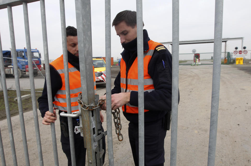 FILE - Two airport police officers use a chain to lock a gate which leads to the airport tarmac, at Brussels international airport, on Feb. 19, 2013. A decade after a brazen diamond heist at Brussels airport, it looks like a near-perfect crime. While one person was convicted to five years in prison and a small part of the loot — estimated at $50 million in 2013 — was recovered, the four remaining suspects were acquitted on appeal Wednesday March 8, 2023, leaving it unclear whether the mastermind will ever be found. (AP Photo/Yves Logghe, File)