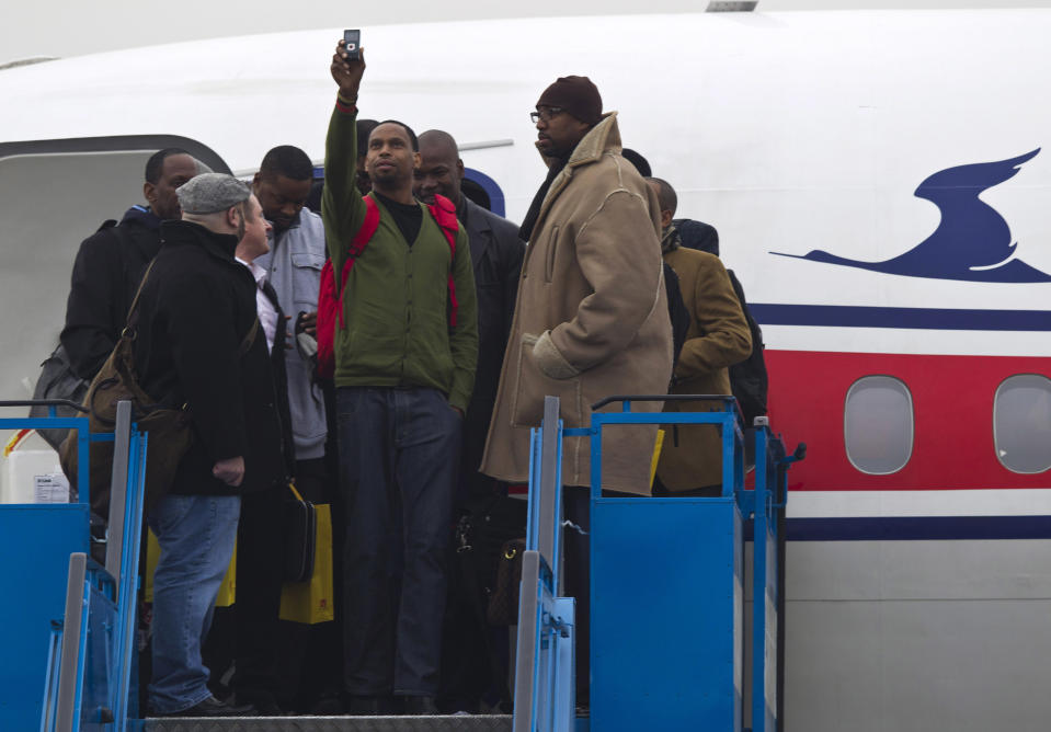 U.S. basketball player Jerry Dupree, center, uses a mobile camera to take a photograph as he and fellow players including former NBA player Vin Baker, right, arrive at the international airport in Pyongyang, North Korea, Monday, Jan. 6, 2014. Dennis Rodman arrived in the North Korean with a squad of former basketball stars in what Rodman calls "basketball diplomacy," although U.S. officials have criticized his efforts. (AP Photo/Kim Kwang Hyon)