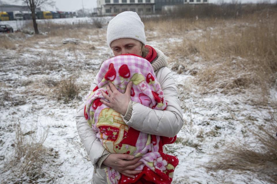 Axana Opalenko, 42, holds Meron, 2 months old, in an effort to warm him after fleeing from Ukraine, at the border crossing in Medyka, Poland, Wednesday, March 9, 2022. U.N. officials said that the Russian onslaught has forced 2 million people to flee Ukraine. It has trapped others inside besieged cities that are running low on food, water and medicine amid the biggest ground war in Europe since World War II. (AP Photo/Visar Kryeziu)