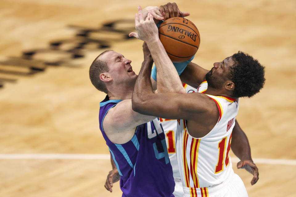 Charlotte Hornets center Cody Zeller, left, and Atlanta Hawks forward Solomon Hill, right, battle for the ball during the third quarter of an NBA basketball game in Charlotte, N.C., Sunday, April 11, 2021. (AP Photo/Nell Redmond)