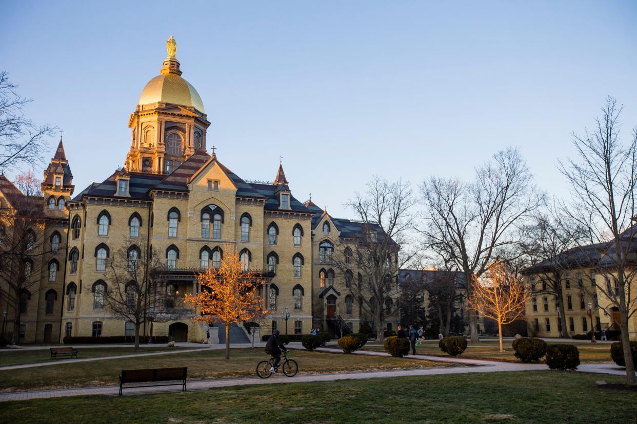 A cyclist goes past the Administration building Wednesday, March 3, 2021, on campus at Notre Dame.