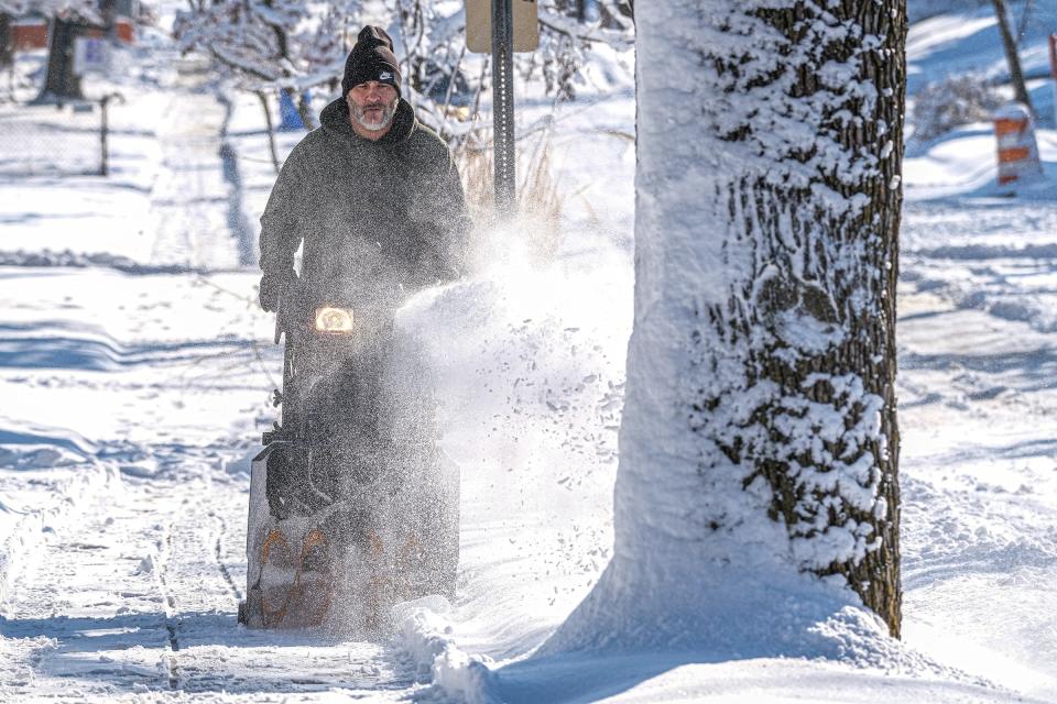 Shane Rennaker from Lansing, clears hsi sidewalk after an overnight storm dumped several inches of wet, heavy snow which left several thousands without power Saturday, Mar. 4, 2023.