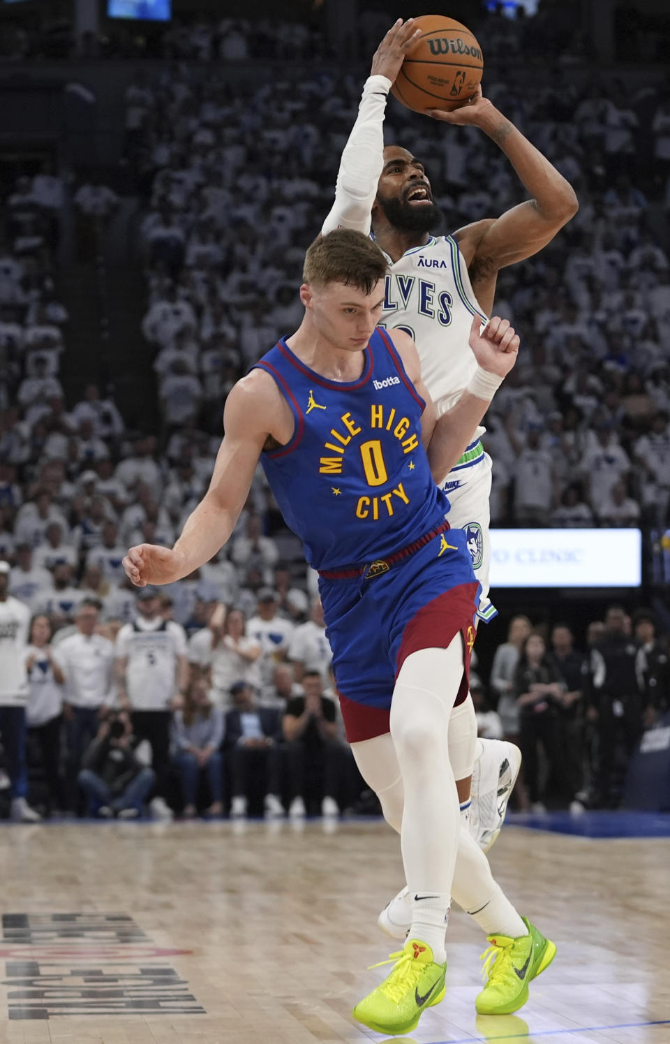 Minnesota Timberwolves guard Mike Conley shoots as Denver Nuggets guard Christian Braun (0) defends during the second half of Game 6 of an NBA basketball second-round playoff series Thursday, May 16, 2024, in Minneapolis. (AP Photo/Abbie Parr)