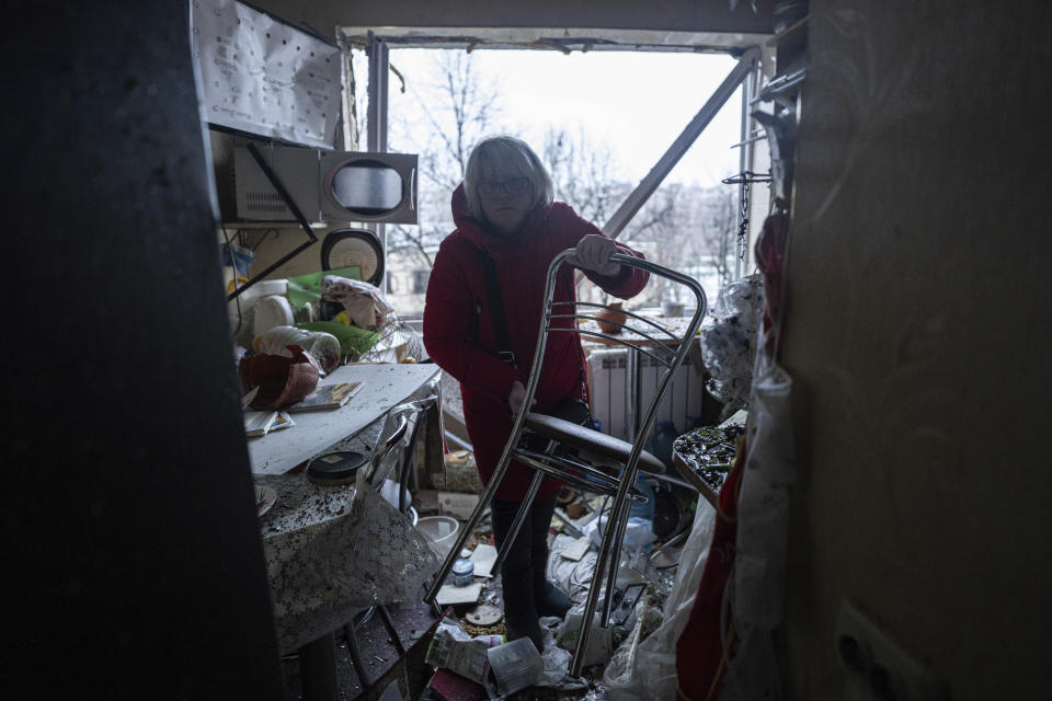 A woman cleans her damaged apartment after a Russian attack at a residential neighbourhood in Kyiv, Ukraine, Wednesday, Dec. 13, 2023. (AP Photo/Evgeniy Maloletka)