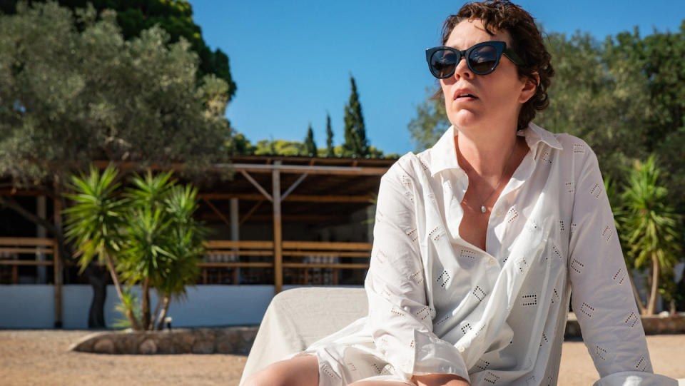 Olivia Colman sits on a lounge chair on the beach in The Lost Daughter