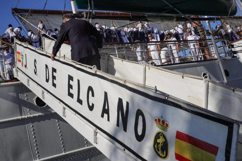 Sailors pack the sails and officers stand in salute as the Spanish consul boards the Juan Sebastian de Elcano.