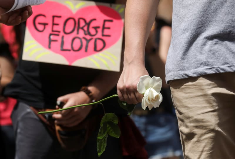 A man holds a white rose as he stands outside during a memorial service for George Floyd following his death in Minneapolis police custody, in Minneapolis
