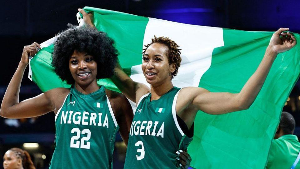 Nigeria's Blessing Ejiofor (L) and Pallas Kunaiyi-Akpanah (R) celebrate with their country's national flag after a Nigerian basketball victory at the Paris 2024 Olympic Games - August 4, 2024