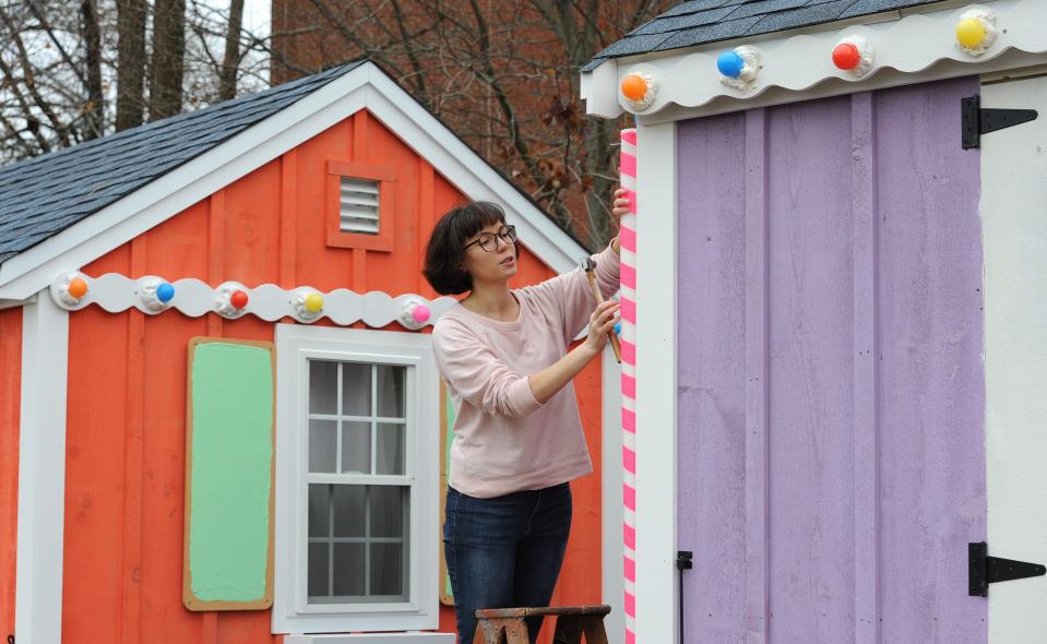 Anne Tochka of Dennis puts some decorative trim up on the Harbor Overlook artist shanties in 2019 after parade organizers commissioned the pieces to turn the artists' shanties into seasonal gingerbread houses.