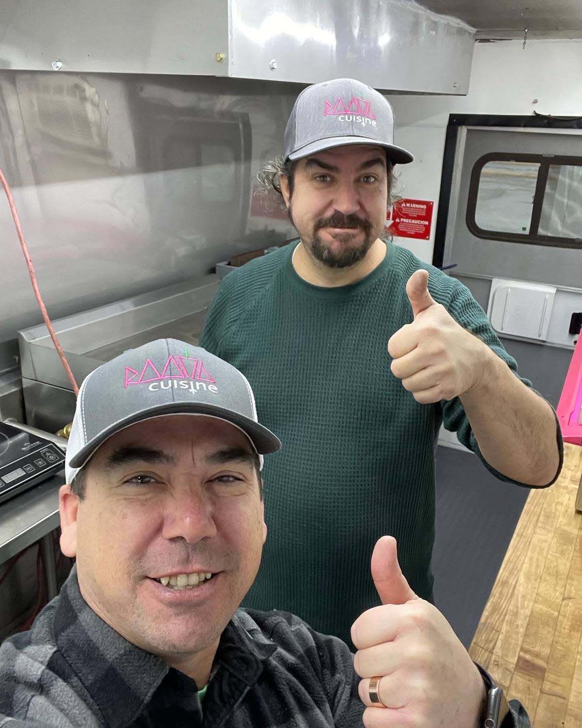 Chefs Scott Kiernan, in the back, and Jason Delasota, give a thumbs up inside their new Root 76 Cuisine food truck that will offer international street foods.