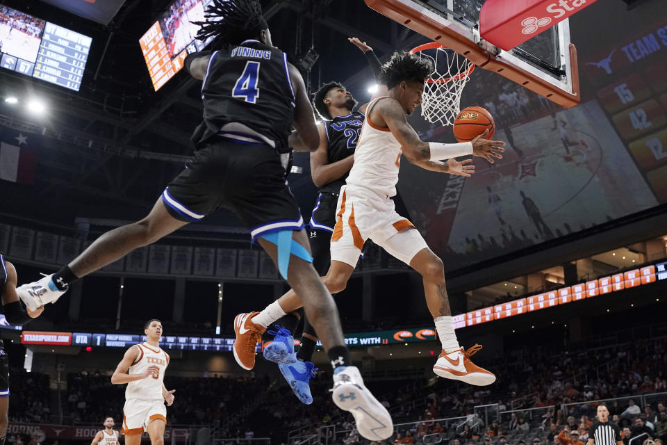 Texas forward Dillon Mitchell (23) is fouled as he drives to the basket between Texas-Arlington guard Akili Vining (4) and forward Shemar Wilson (22) during the second half of an NCAA college basketball game in Austin, Texas, Monday, Jan. 1, 2024. (AP Photo/Eric Gay)