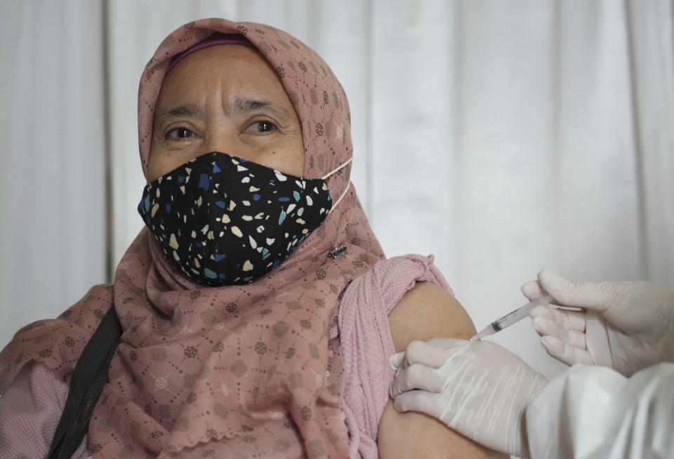 A woman receives a booster shot of Pfizer COVID-19 vaccine during a third dose vaccination campaign at a South Tangerang Regional General Hospital in Tangerang, Indonesia, Wednesday, Jan. 12, 2022. Indonesia kicked off a COVID-19 booster campaign for the general public on Wednesday, prioritizing third shots for the elderly and people with compromised immune systems. (AP Photo/Tatan Syuflana)