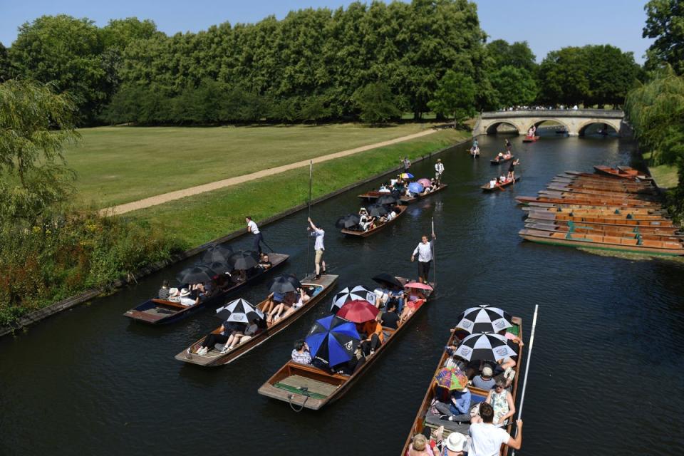 Cambridge: People use umbrellas to shield from the sun as they punt along on the River Cam (PA)