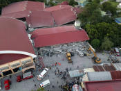 Workers use heavy equipment to clear an area as rescue efforts continue for people still trapped inside a small collapsed building at Porac town, Pampanga province, northern Philippines Monday, April 22, 2019. A strong 6.1 magnitude earthquake in the north Philippines on Monday trapped some people in a collapsed building, damaged an airport terminal and knocked out power in at least one province, officials said. (AP Photo/Vhic Y Naluz)