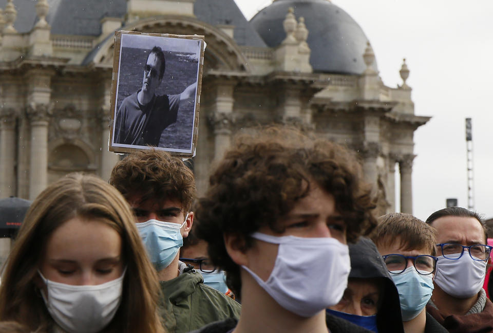 A portrait of Samuel Paty is held up as people gather on Republique square in Lille, northern France, Sunday Oct. 18, 2020. Demonstrators in France on Sunday took part in gatherings in support of freedom of speech and in tribute to a history teacher who was beheaded near Paris after discussing caricatures of Islam’s Prophet Muhammad with his class. (AP Photo/Michel Spingler)