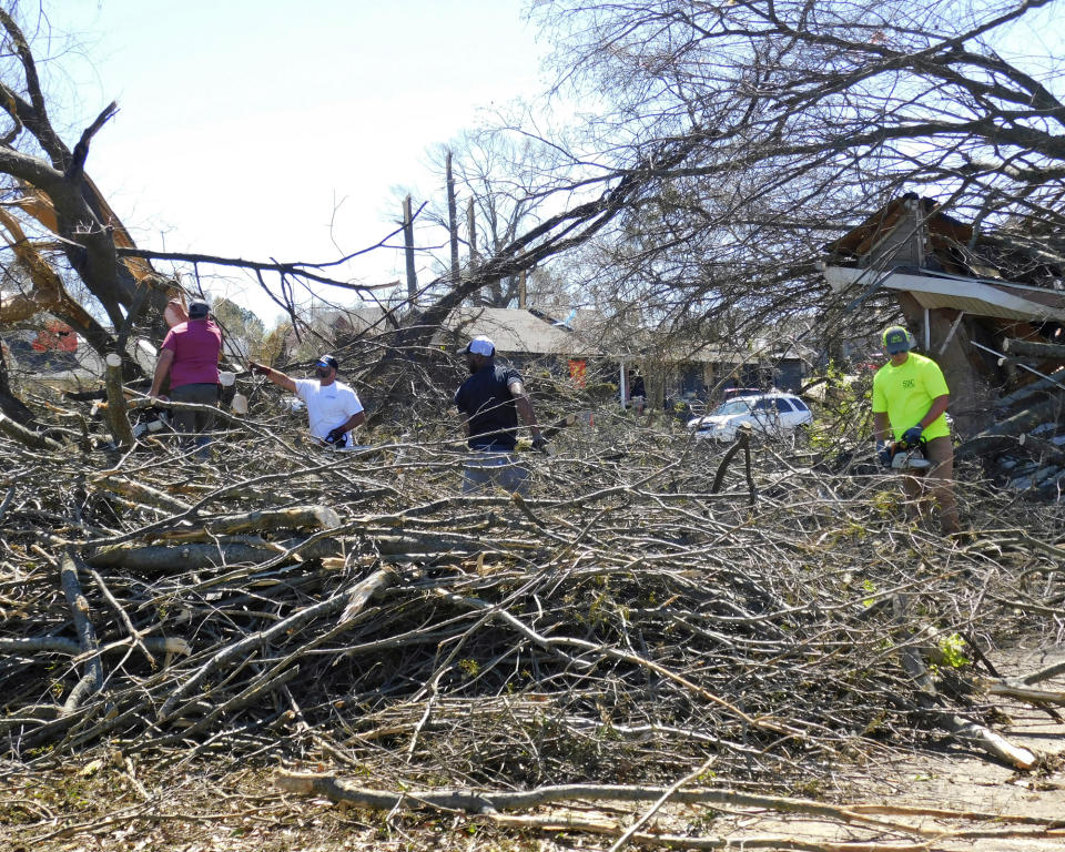 Volunteers cut up trees that were down at the corner of E. Bridges Avenue and N. Killough Road in Wynne, Ark., Saturday, April 1, 2023, following severe weather the previous night. (Nena Zimmer/The Jonesboro Sun via AP)