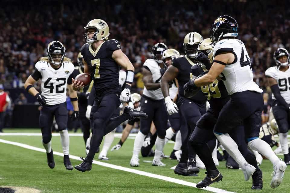 New Orleans Saints quarterback Taysom Hill (7) runs for a 1-yard touchdown past Jacksonville Jaguars safety Andrew Wingard (42) and linebacker Chad Muma, right, in the second half of an NFL football game in New Orleans, Thursday, Oct. 19, 2023. (AP Photo/Butch Dill)