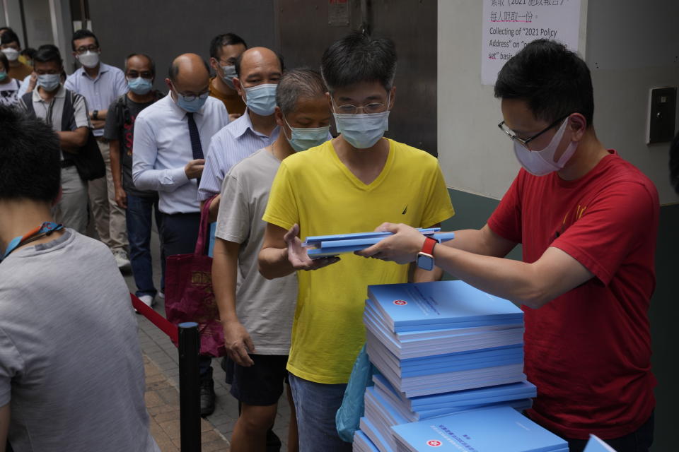 People line up to collect the copies of the policy address after Hong Kong Chief Executive Carrie Lam delivering her policy address at the Legislative Council in Hong Kong, Wednesday, Oct. 6, 2021. Lam announced a major development plan Wednesday for Hong Kong's border area with mainland China in the last annual policy address of her current term. (AP Photo/Kin Cheung)