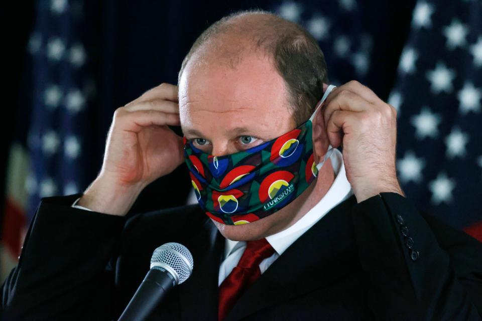 Colorado Gov. Jared Polis puts on his face mask after a news conference May<TH>28 in Denver about the state’s efforts against the new coronavirus.
