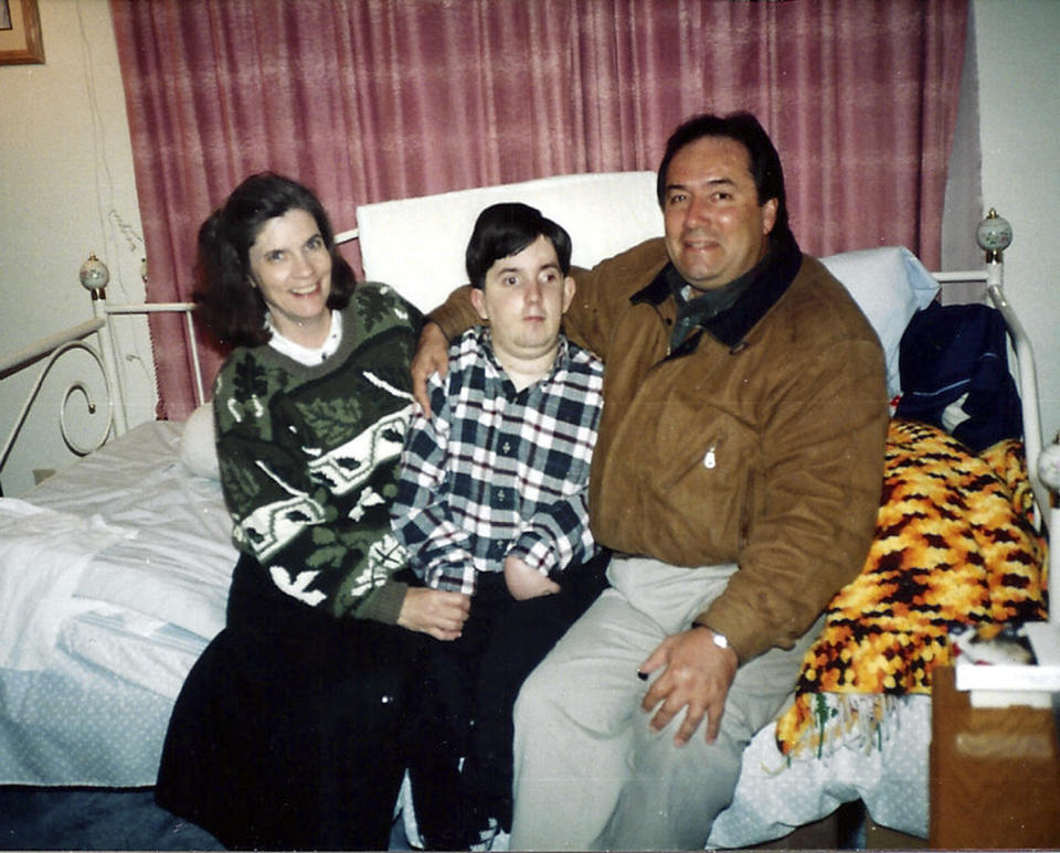 This undated handout photo provided by Paul Cortez shows 15-year-old Mikey Cortez, center, and his parents, Paul and Roonie Cortez. As his 7-year-old son Mikey lay in a hospital bed on life support, the victim of a drunk driver who had smashed into the car he was riding in, Paul Cortez took the boy's hand and made a solemn promise to God: If his son survived, no matter in what condition, he and his family would always be there for him. Although he would never emerge from the persistent vegetative state his father had found him in that night, Mikey’s family was not only there for him but also gave him a full life. A life, as it turned out, not all that different from anybody else’s, with cross-country family vacations and visits to Disneyland.(AP Photo/Courtesy Cortez Family)